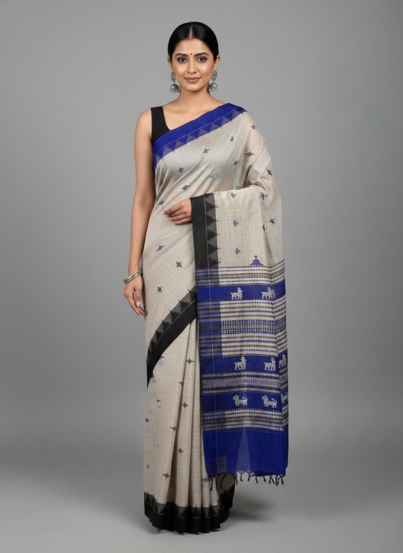Woman wearing a traditional saree with blue and black patterns on a gray background