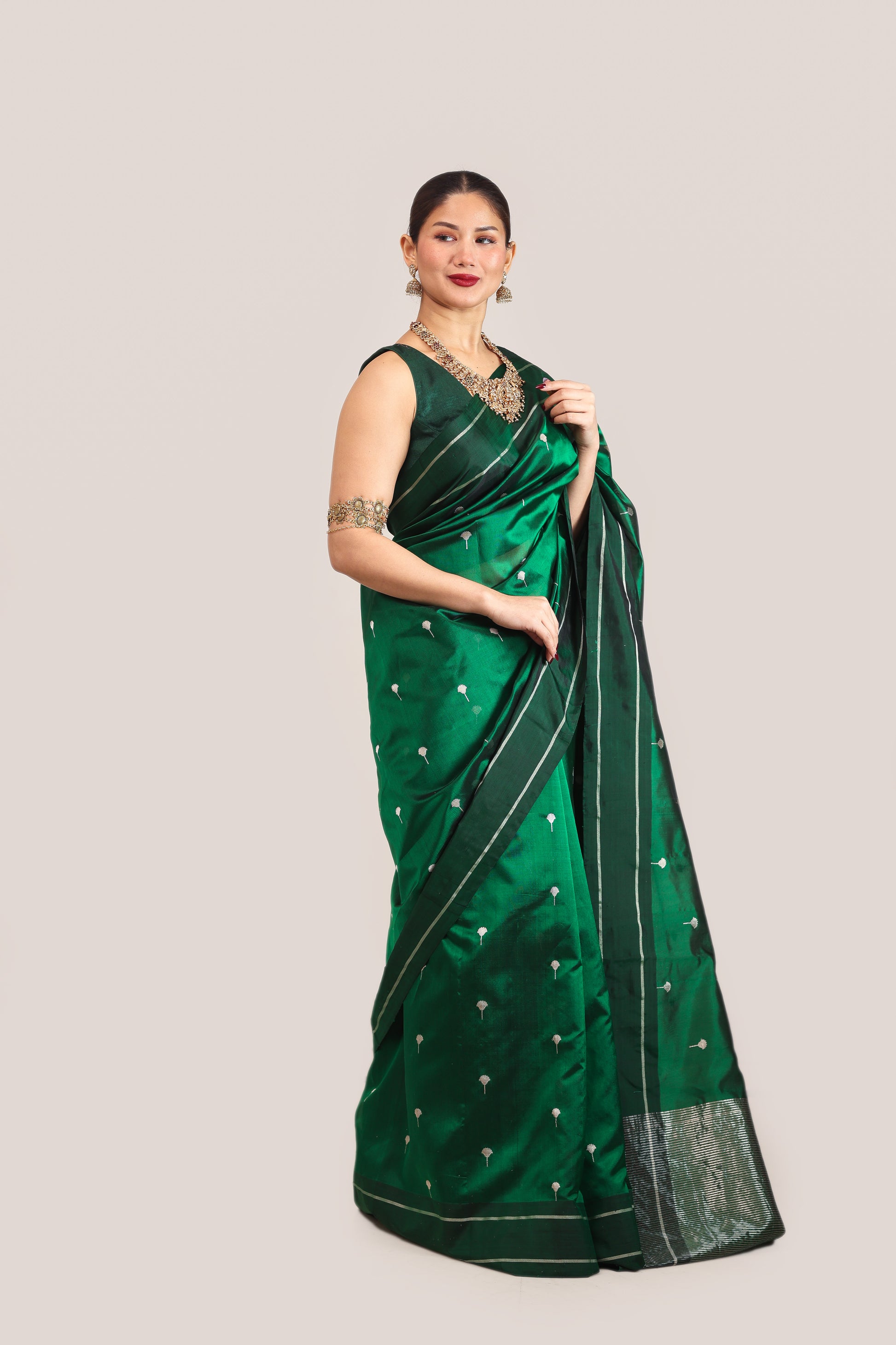 Woman wearing a green saree with a white blouse on a light gray background