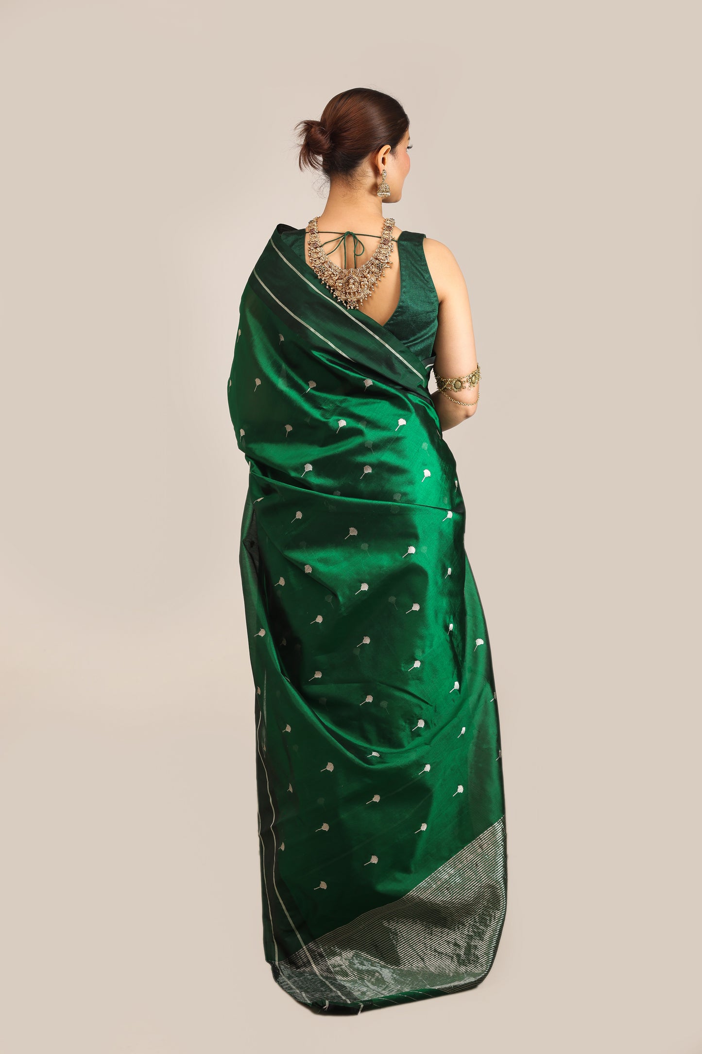 Woman wearing a green saree with a subtle pattern on a beige background