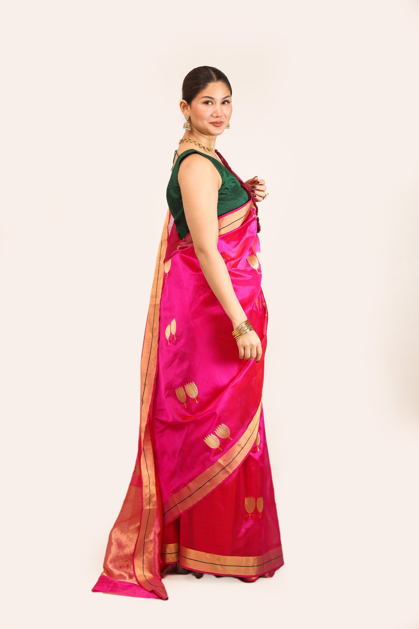 Woman wearing a pink saree with a green blouse against a white background