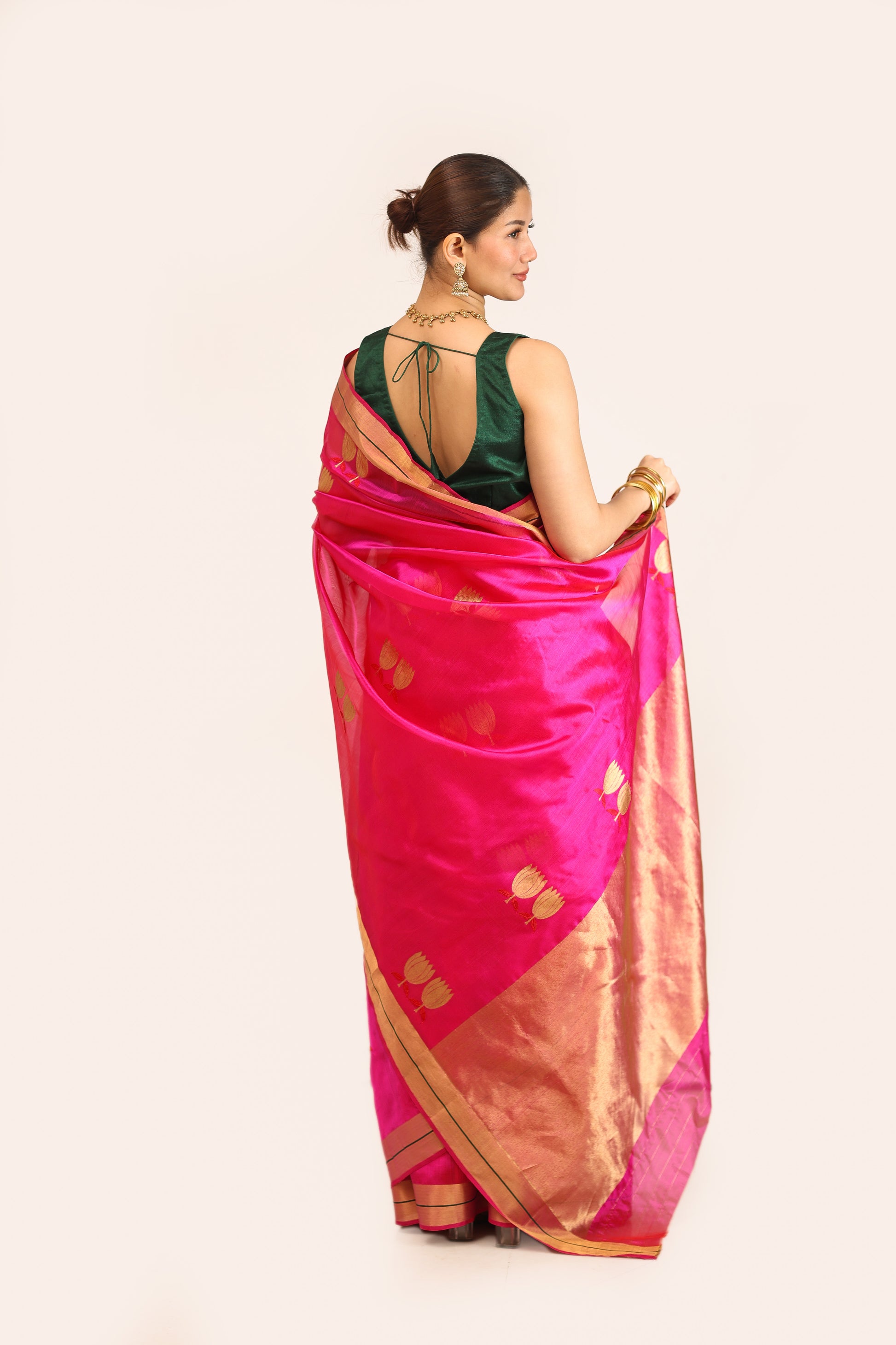 Woman wearing a pink saree with gold patterns on a white background