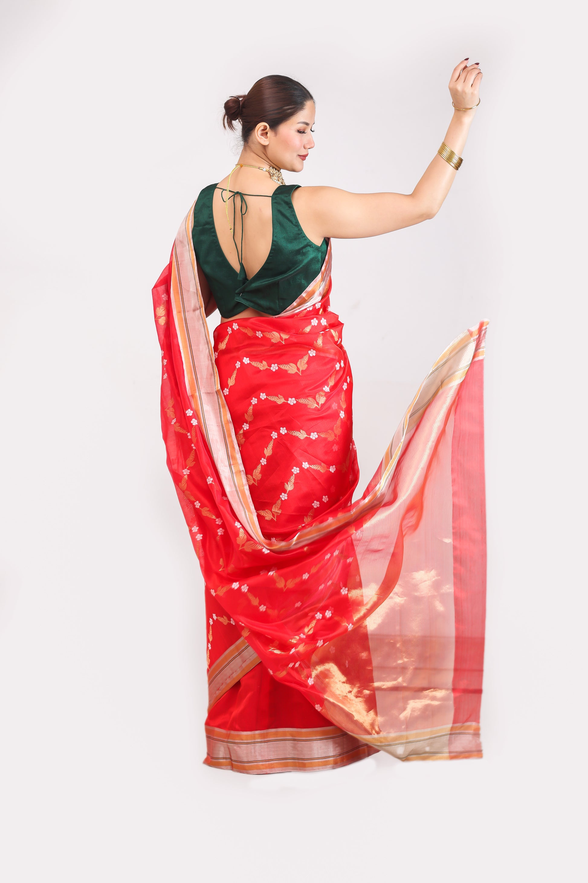 Woman wearing a red saree with a green blouse against a white background