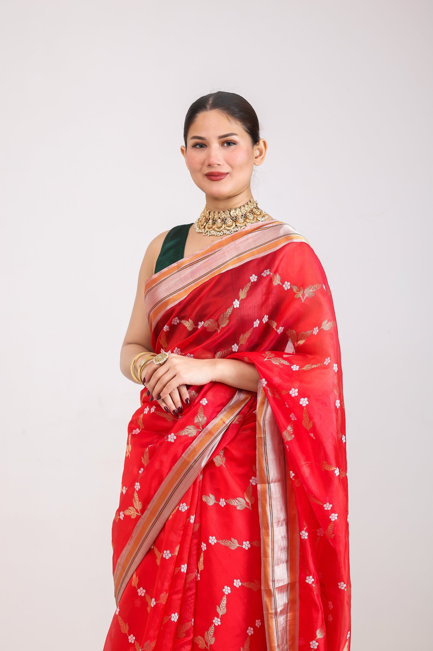 Woman wearing a red saree with gold patterns on a white background