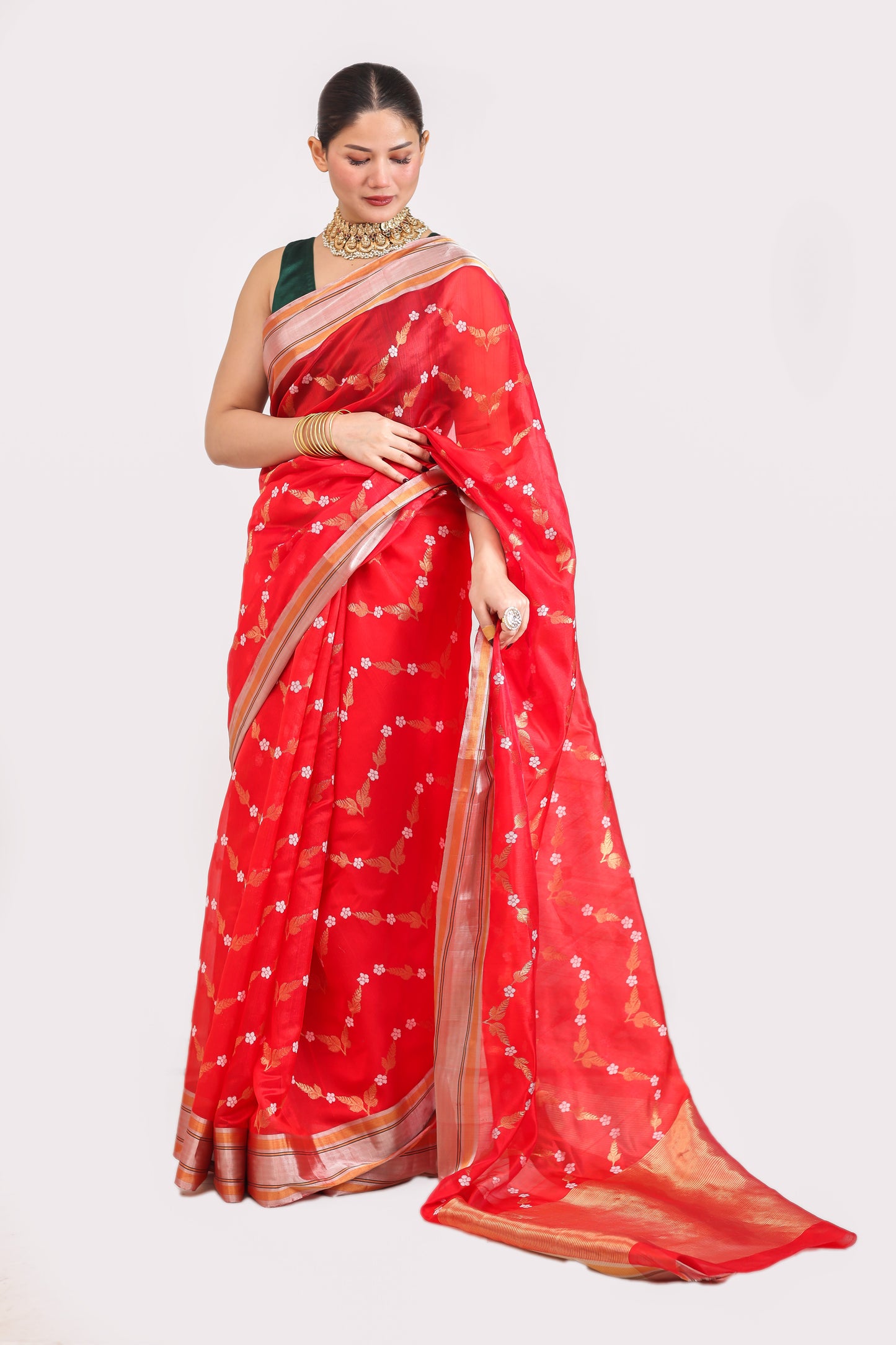 Woman wearing a red saree with white patterns on a plain background