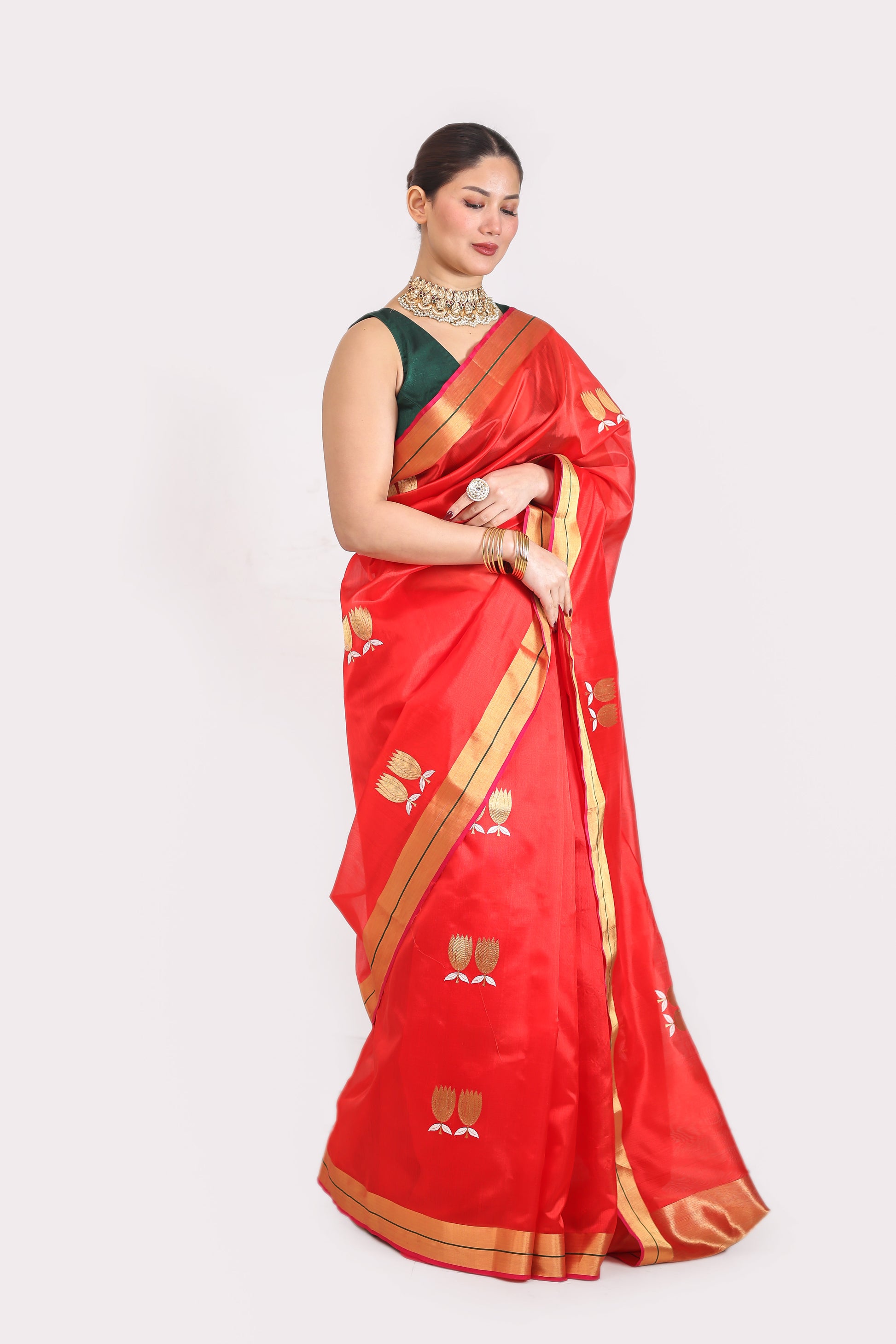 Woman wearing a red saree with gold patterns on a white background