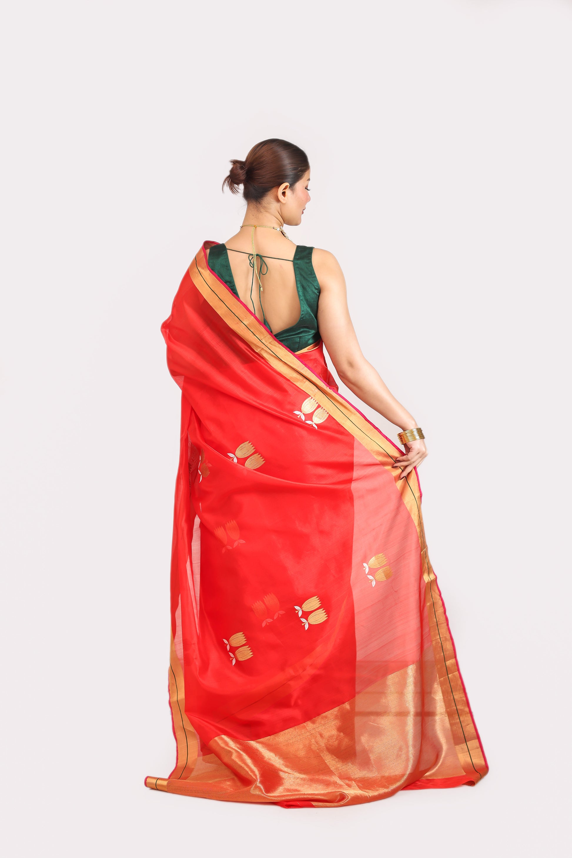 Woman wearing a red saree with gold border on a white background