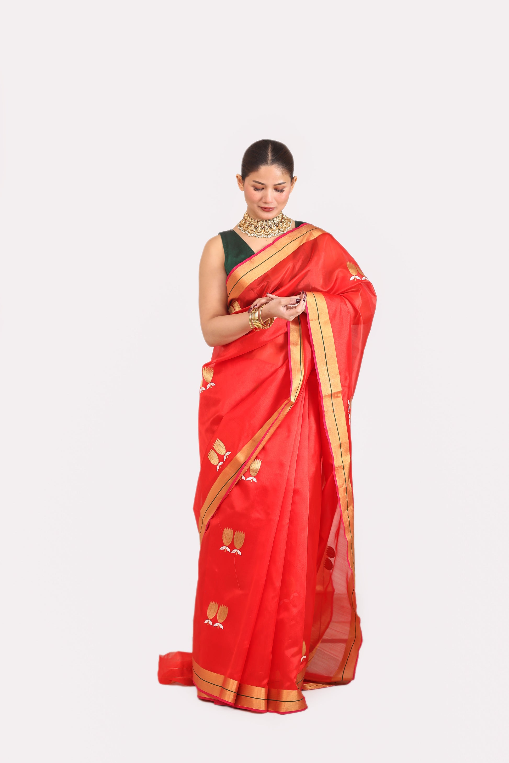 Woman wearing a red saree with gold border on a white background
