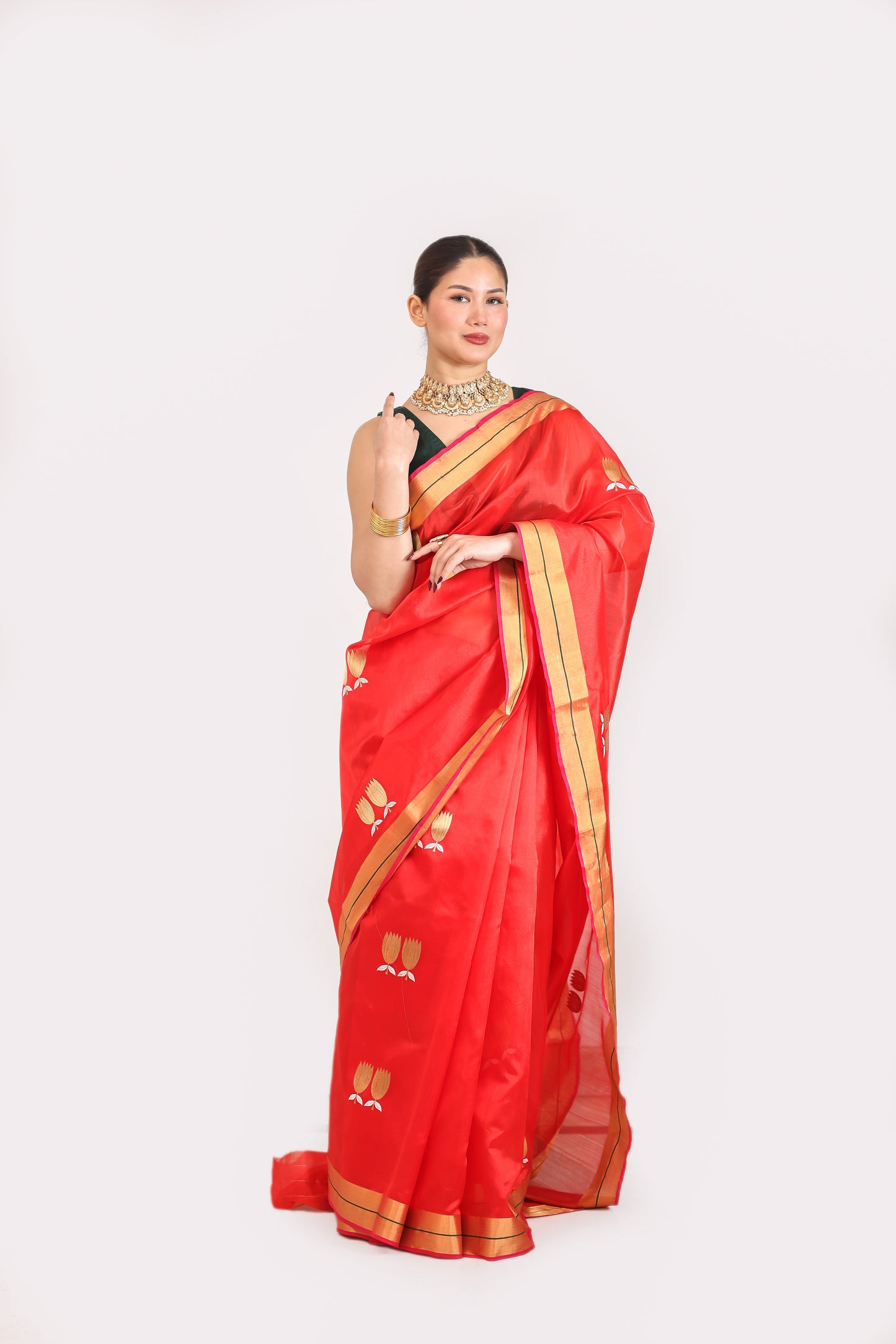 Woman wearing a red saree with gold border on a white background