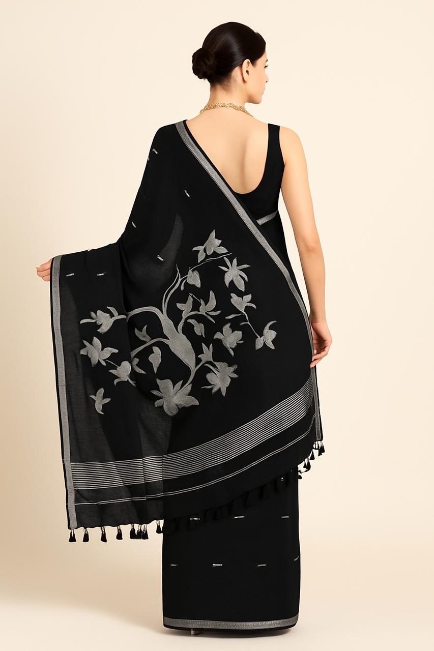 Woman wearing a black saree with floral patterns on a beige background