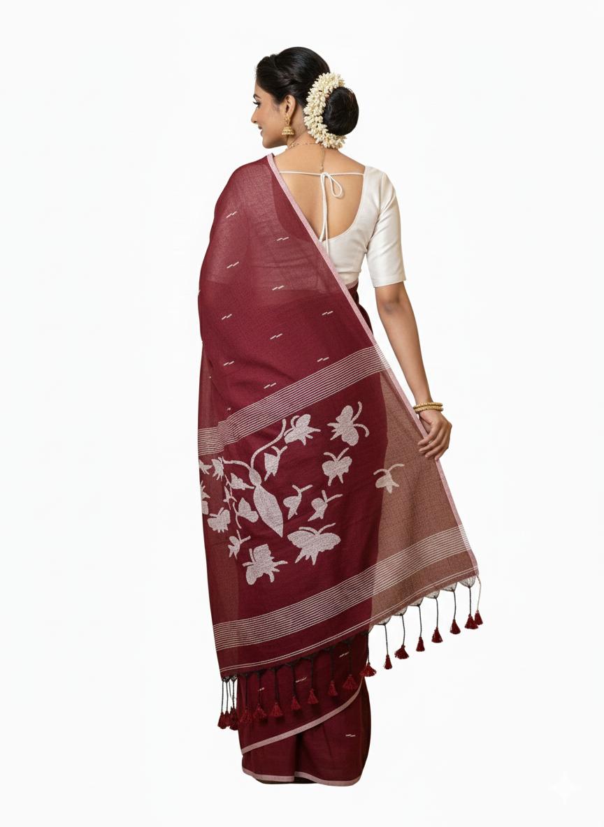 Woman wearing a maroon saree with white floral patterns on a white background