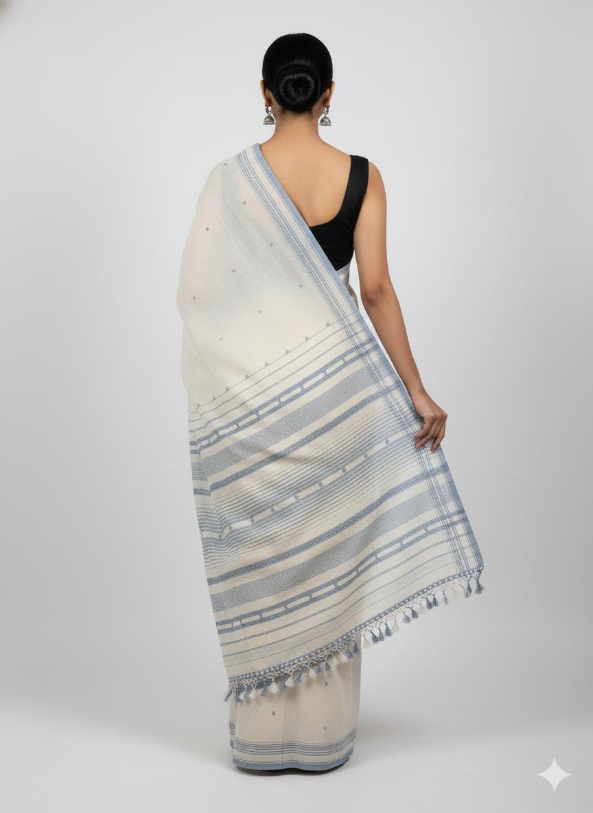Woman wearing a white saree with blue stripes on a plain background