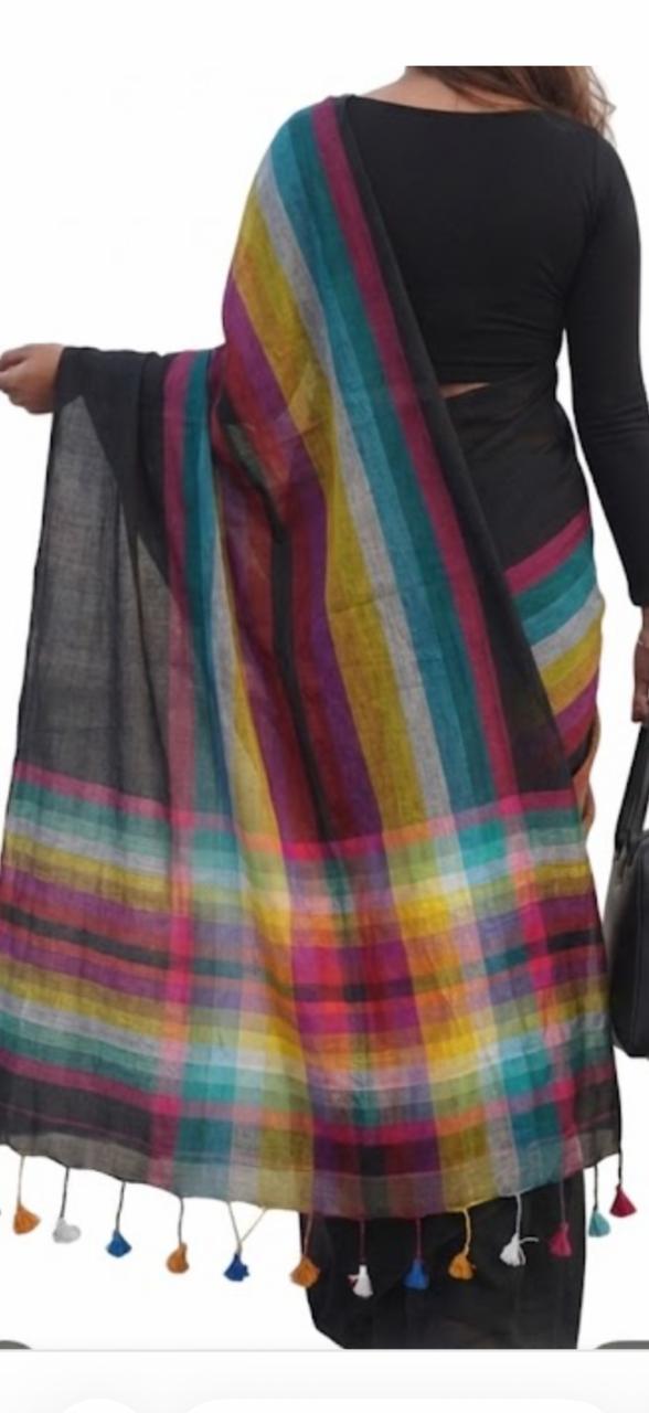 Person wearing a colorful striped shawl with tassels on a plain background